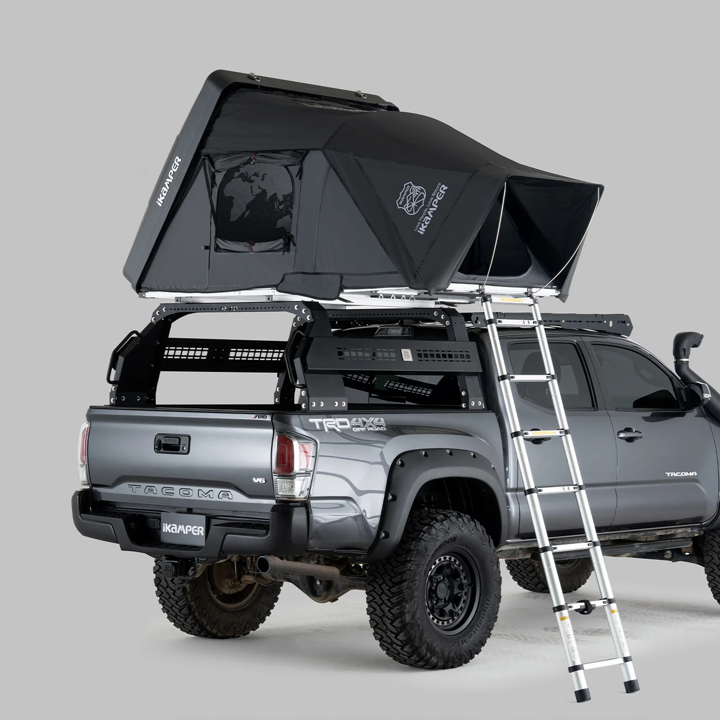 Skycamp DLX Mini tent is shown in black over a silver pickup truck cab. An ultralight aluminum ladder provides entry to the truck-top camper.