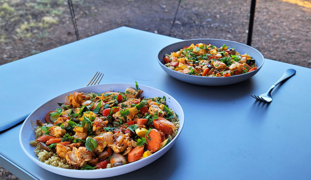 Harissa spiced vegetables and couscous is shown plated on a table.