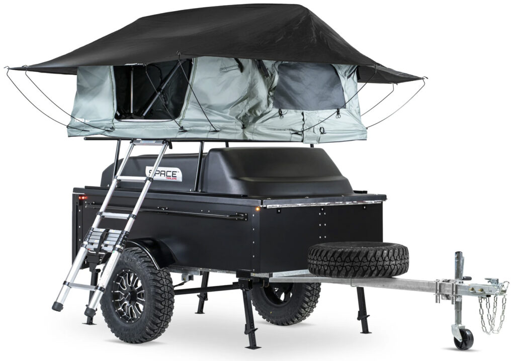 The SPACE camper trailer is shown in black with cover on and tent assembled above it, with a rain fly.