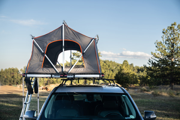 Meadowlark XL Roofnest car-top tent in gray with orange trim is shown over an SUV with the windows open